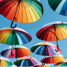 Umbrellas in rainbow color on blue sky background